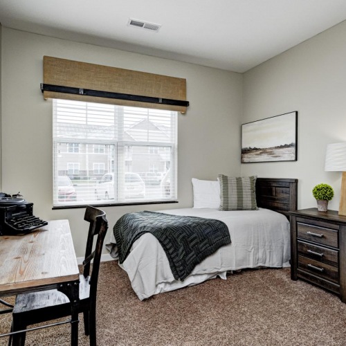 Relax and recharge in beautiful and spacious bedrooms a bedroom with a bed desk and a lamp